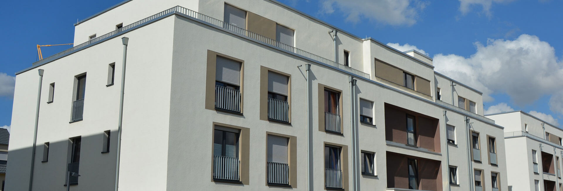 Blick von außen auf das inklusive Wohnhaus: Ein modernes, weiß gestrichenes Gebäude mit braunen Farbakzenten.